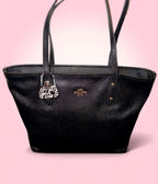 Black handbag with a purse hook on a pink background