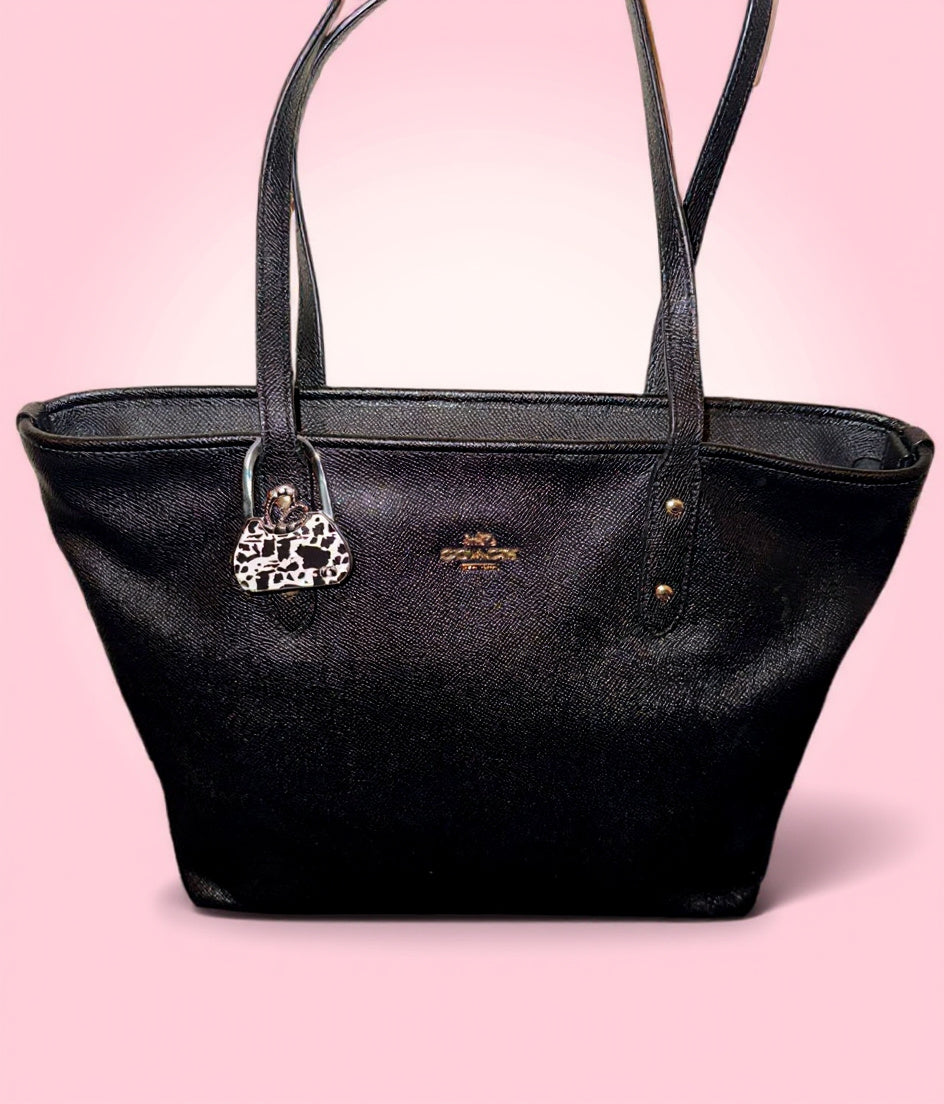 Black handbag with a purse hook on a pink background