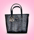 Black handbag with a decorative purse bag hook on a pink background